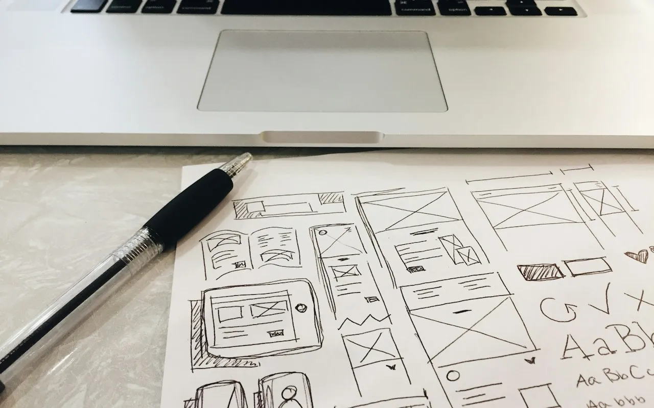 Wireframe-Skizzen auf Papier neben einem Laptop